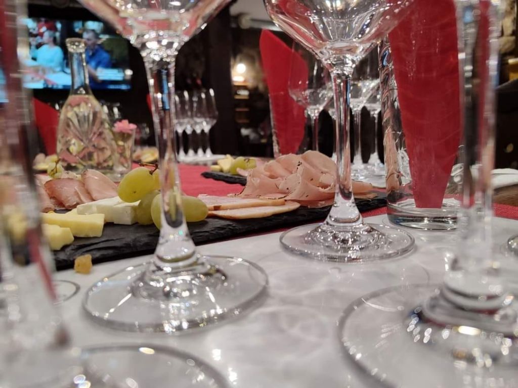 Високи чаши на подредена маса до плато с колбаси и сирена.